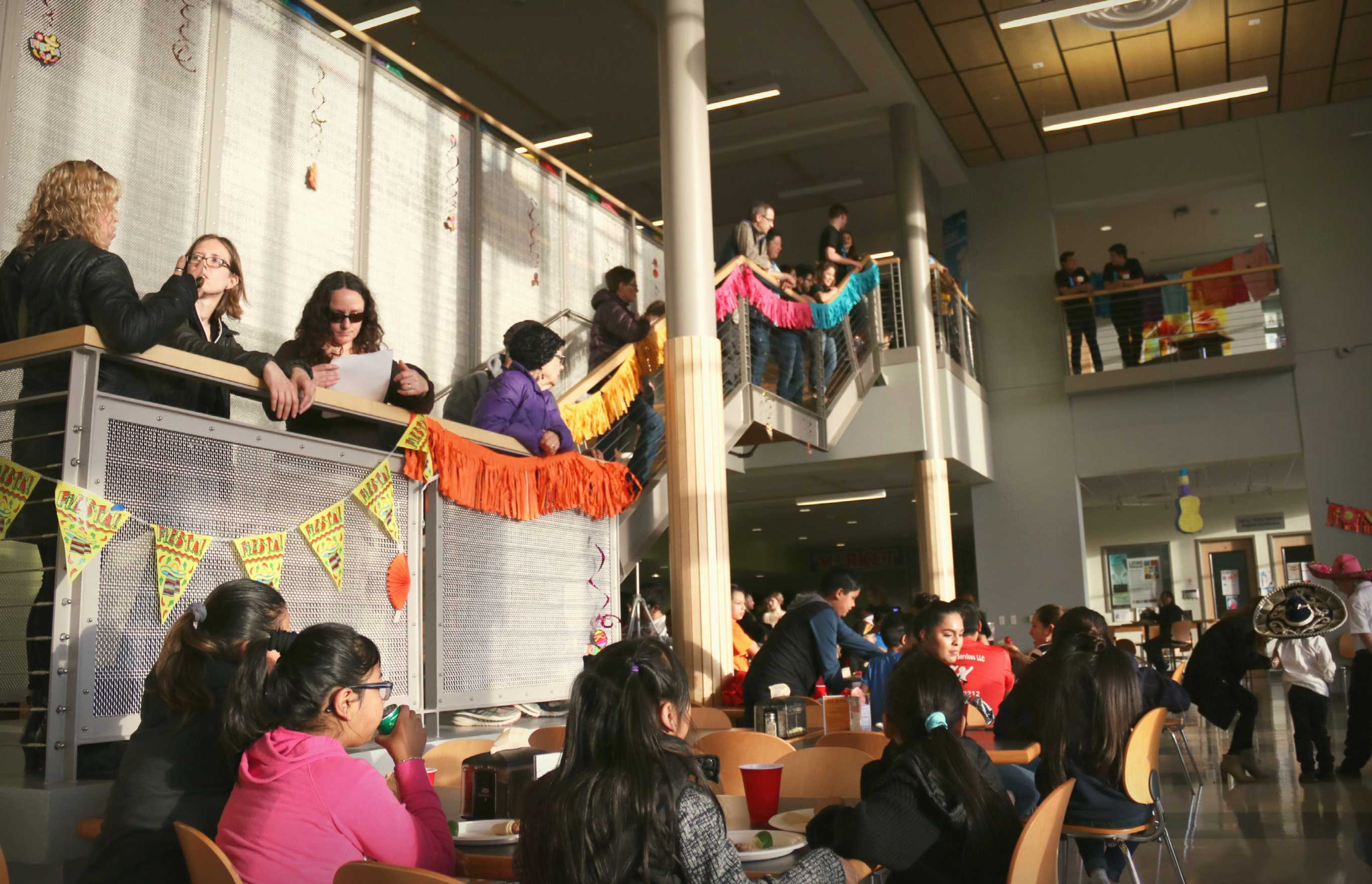Attendees of the Latino Fiesta gather around cafeteria tables and on the stairs of the Campus Center to watch the dance performances.