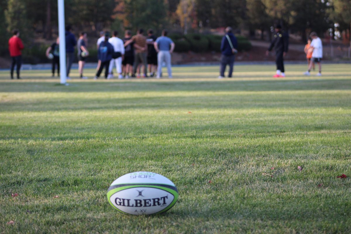 photo of rugby ball with team in the background.