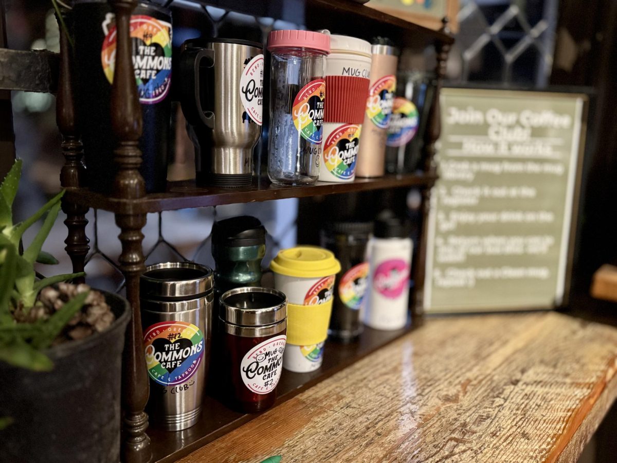 Two rows of mugs sit patiently on The Commons' Mug Club Shelf  awaiting for their next customer.
